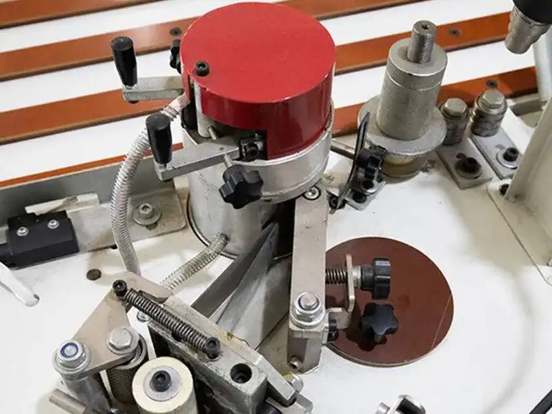 Detailed view of the HE-305B manual bevel edge bander featuring a 30 to 90 degree high-precision adjustable bevel trimming and scraping station.