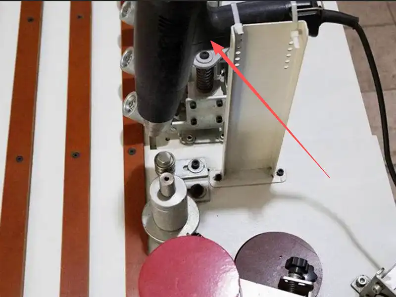 Integrated industrial heat gun auxiliary system on the HE-305B manual bevel edge bander pre-heating thick PVC tape for maximum flexibility.
