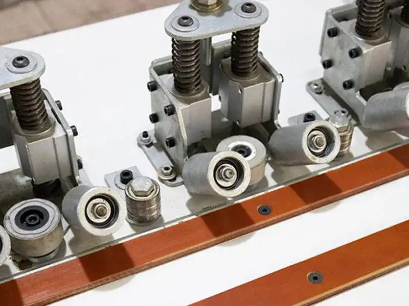 Top-down view of the HE-305B manual bevel edge bander showing the omnidirectional multi-angle pressure rollers and the heavy-duty spring-guided feeding tracking system.