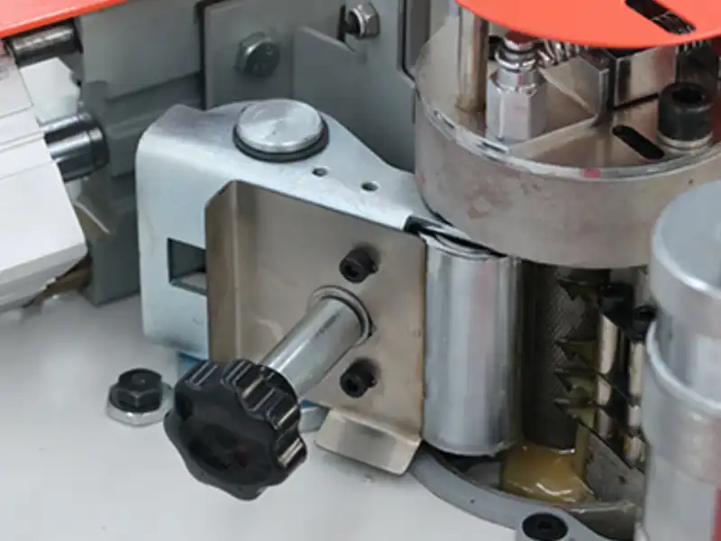 Detailed view of the HE-305U micro-adjustable glue volume regulator dial integrated with a heavy-duty bearing-type pressure plate on the adhesive station.