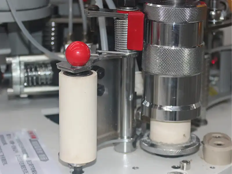 Heavy-duty secondary auxiliary pressure rollers on the HE-370 edge bander applying uniform compaction force to the newly glued edge tape