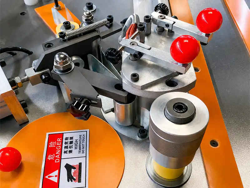 Heavy-duty pneumatic guillotine shearing unit on the HE-305 manual edge bander, showing the high-rigidity cutting blade slicing thick PVC tape.
